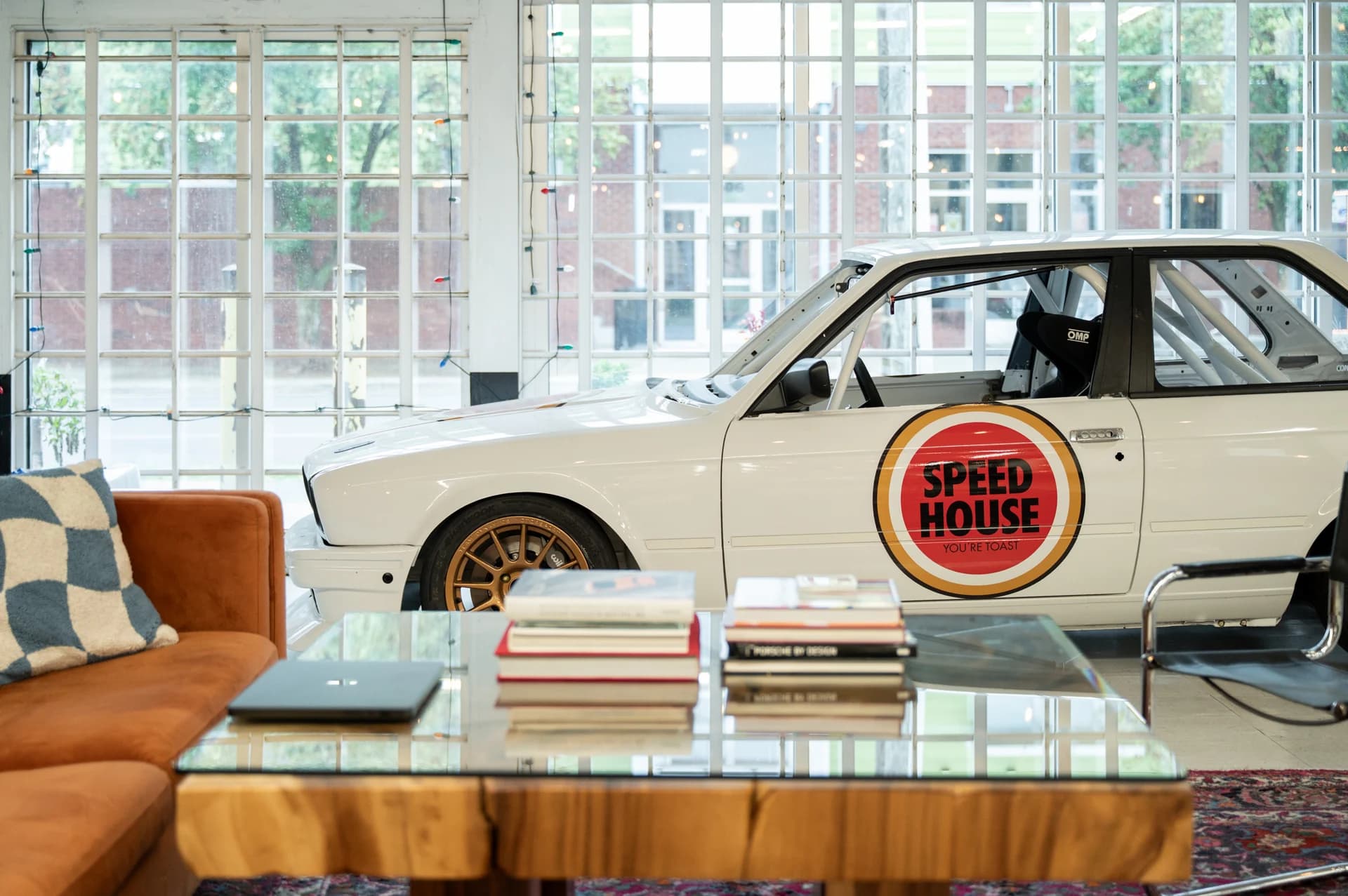 White BMW race car with Speed House branding in the workshop lounge