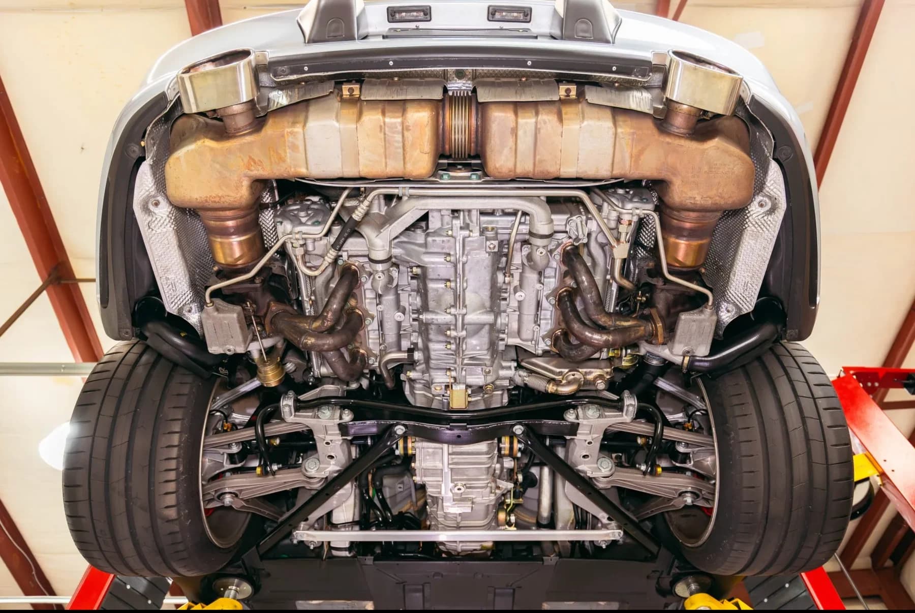 Porsche undercarriage on a workshop lift showing the exhaust, drivetrain and suspension