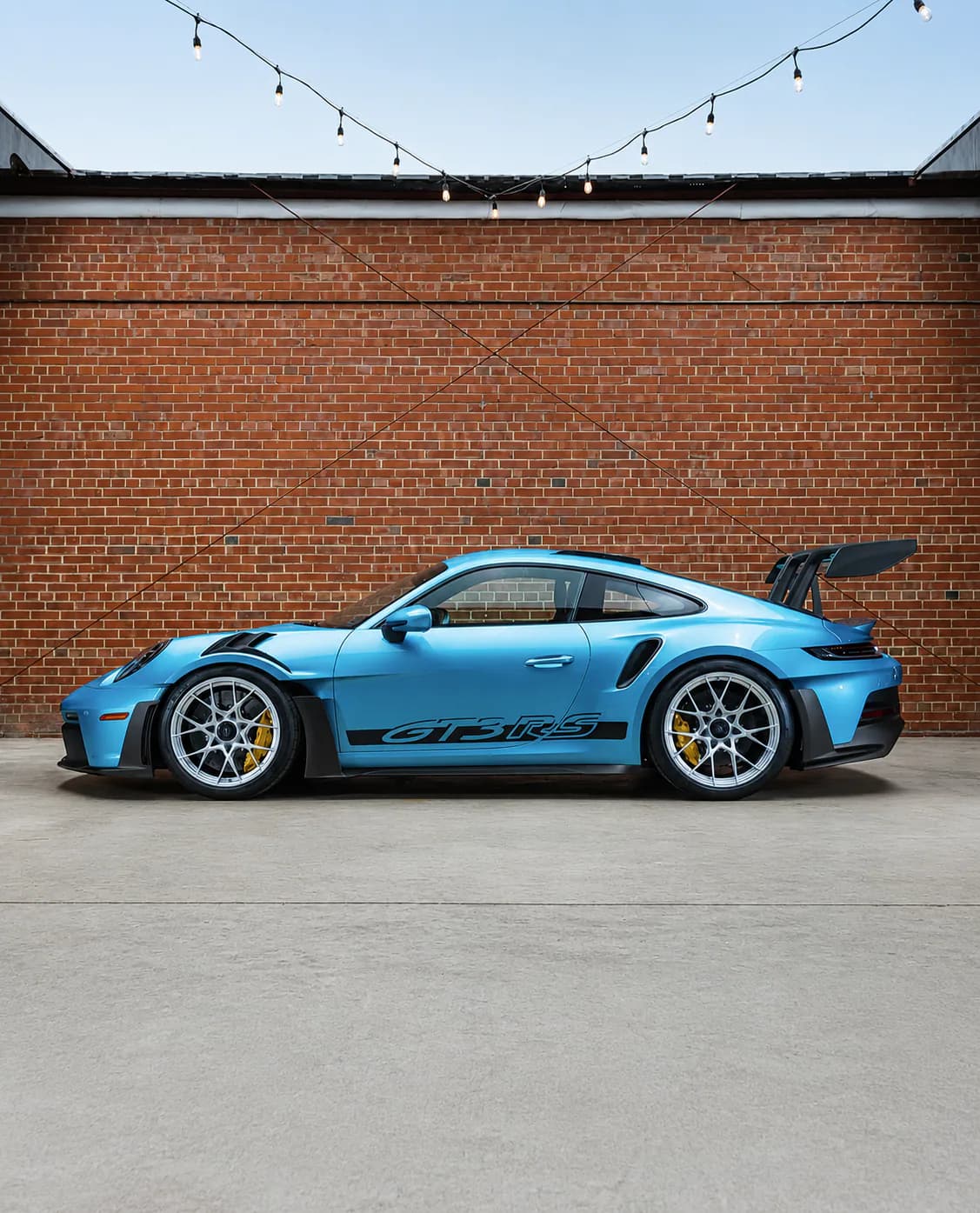 Blue Porsche photographed against the brick wall inside the Speed House showroom
