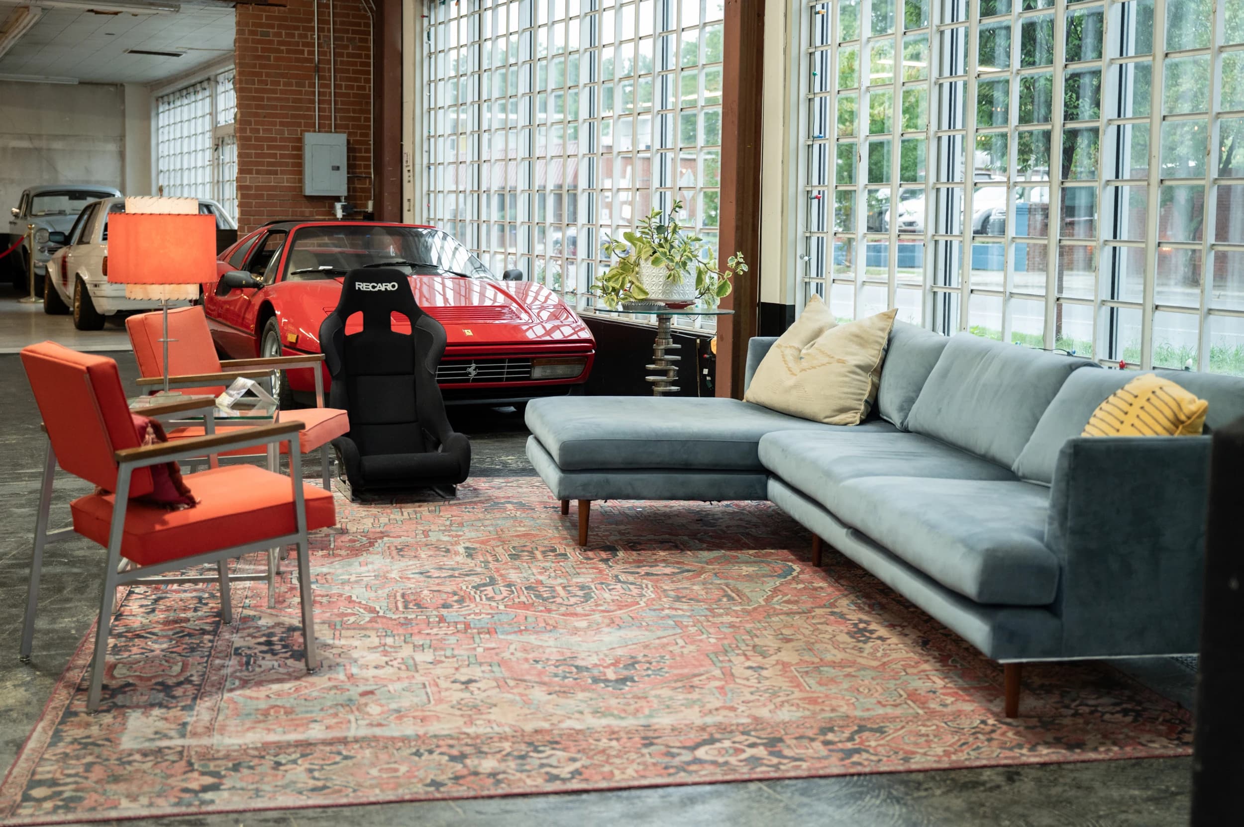 Red Ferrari beside the blue sofa and orange chairs in the Speed House clubhouse