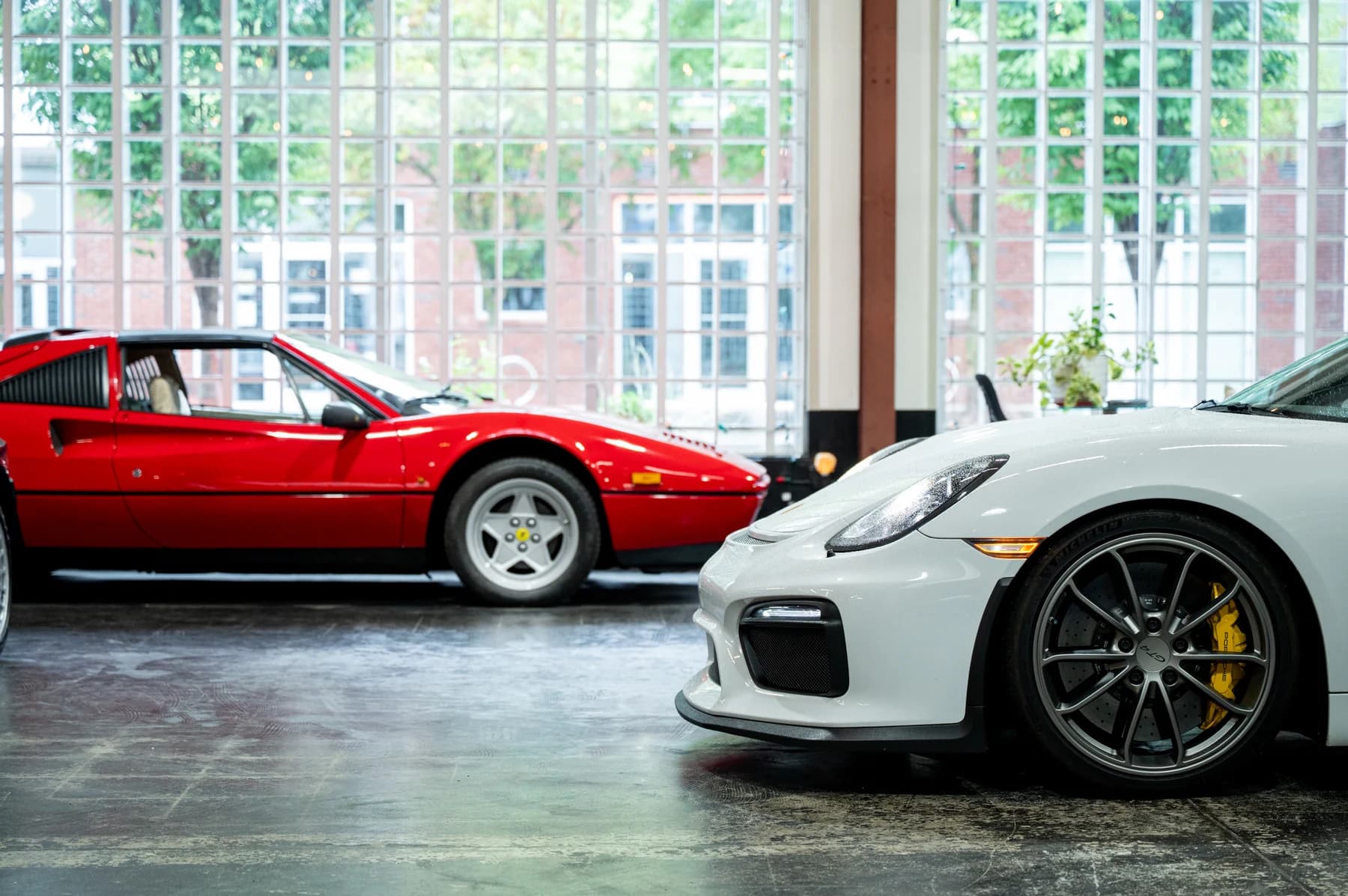 Red Ferrari and white Porsche inside the Speed House workshop