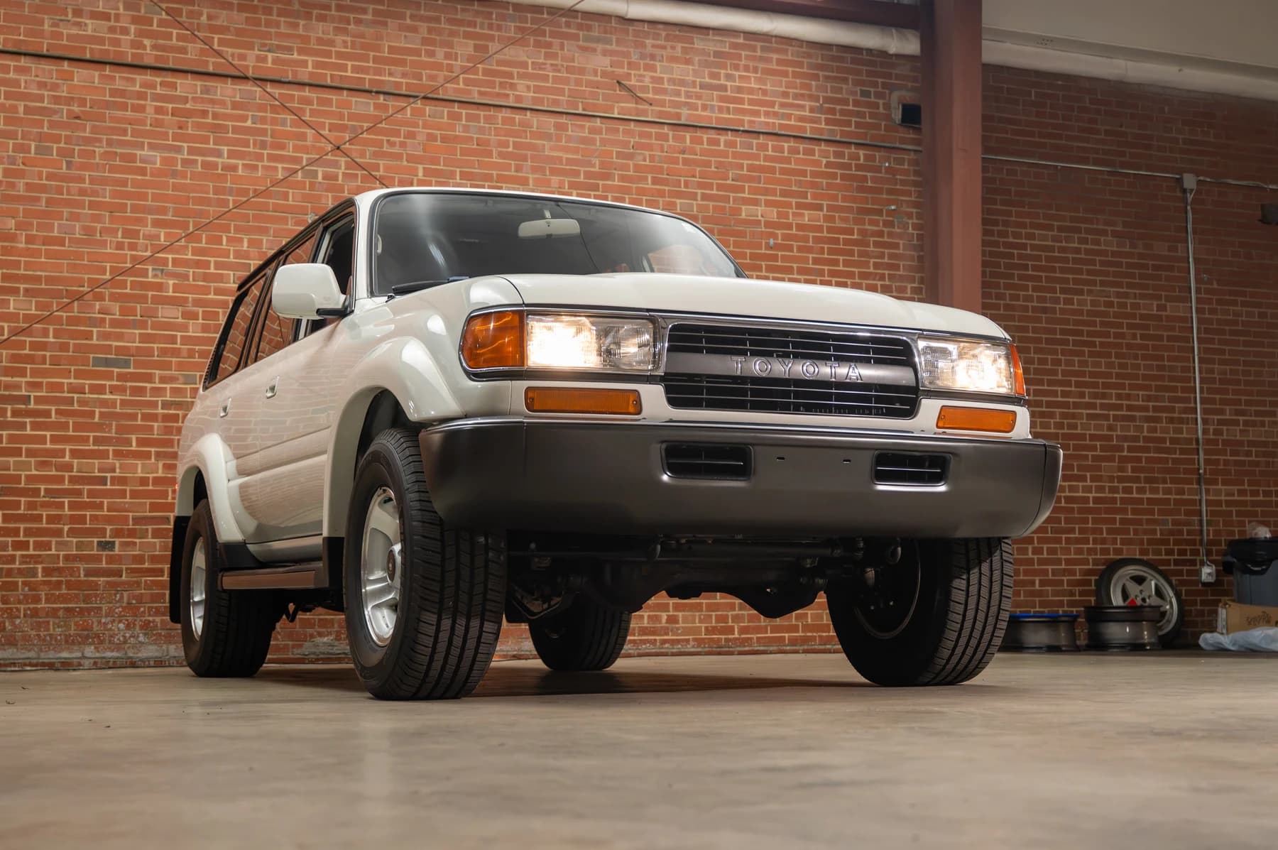 White Toyota Land Cruiser with its headlights on inside the Speed House workshop